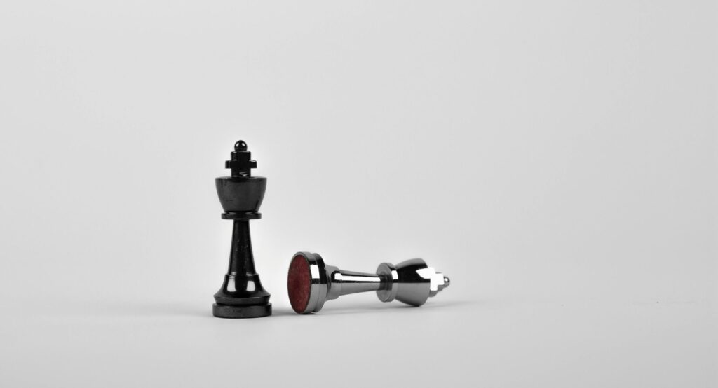 Close-up of chess king piece standing with a fallen piece symbolizing strategy and victory.